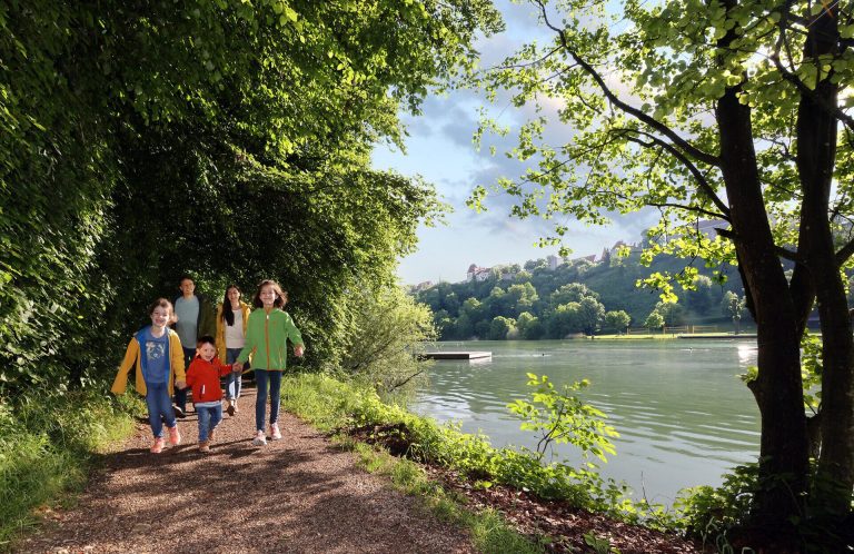 Idyllischer Badesee Wöhrsee direkt unterhalb der Burg Burghausen im Sommer.