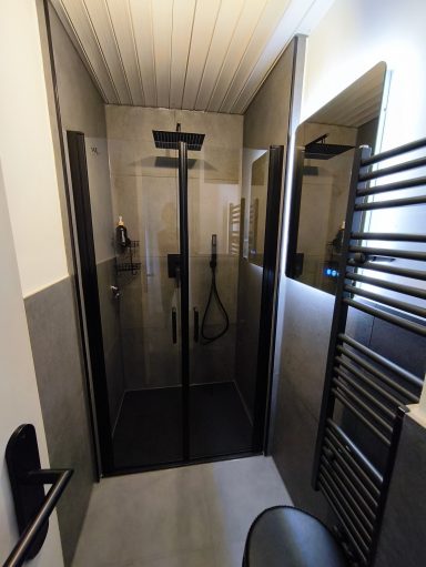 Moderne, begehbare Dusche mit edlen schwarzen Armaturen und Handtuchwärmer im Badezimmer der Ferienwohnung Burgperle in Burghausen.